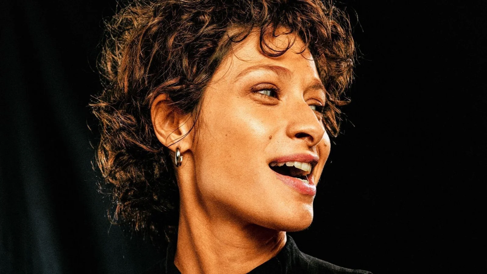 Luisa Arraes caracterizada como Cássia Eller, cantando e tocando violão no palco