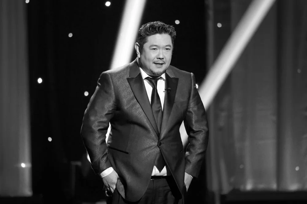Eric Bauza em preto e branco, de smoking, durante cerimônia do Emmy