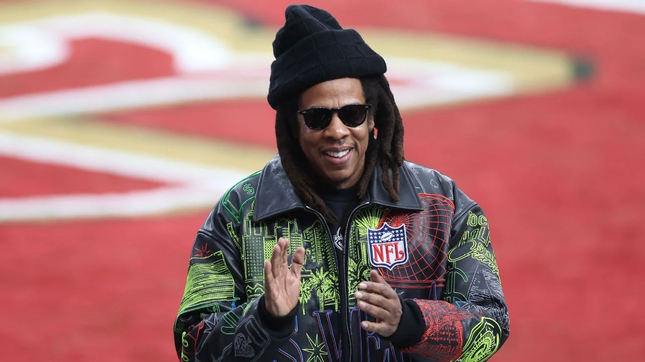 Jay-Z sorrindo e aplaudindo em evento da NFL